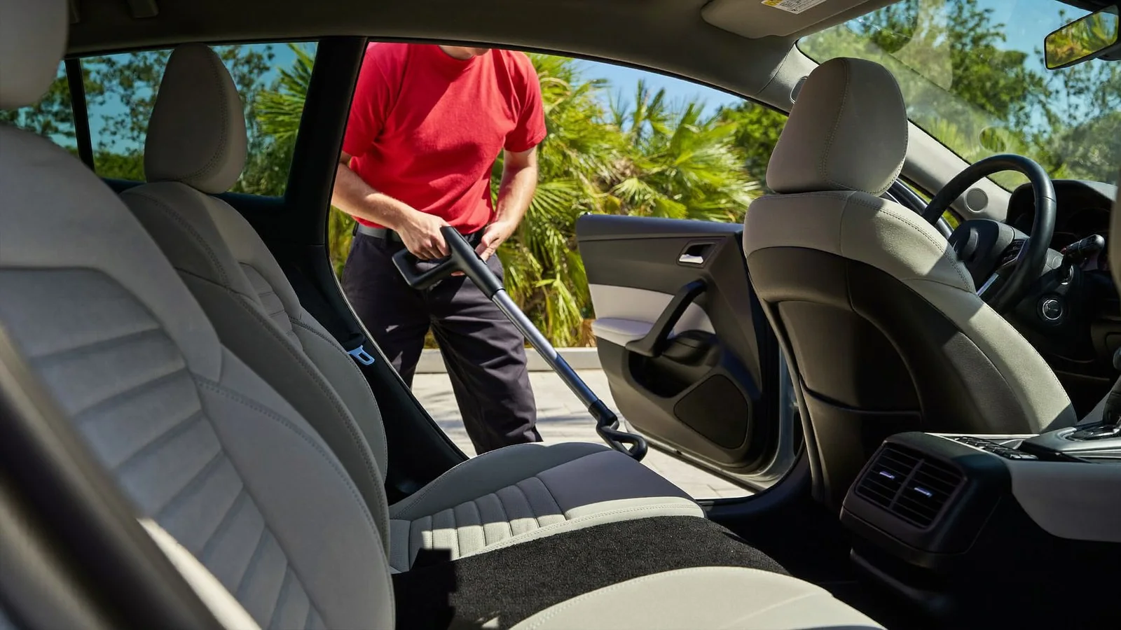 Crew member cleaning sand out of a car's carpet during an interior detail